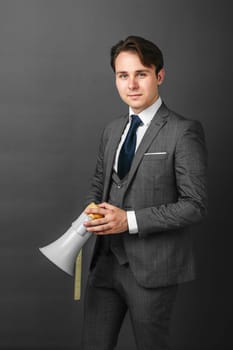 Business and finance concept. Portrait of a businessman who holds a megaphone in his hands. Light background