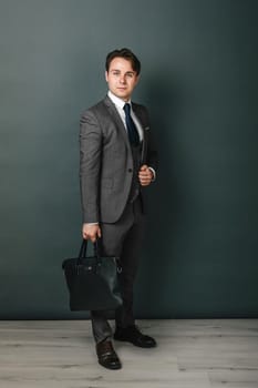 Business and finance concept. Portrait of a businessman who is holding a briefcase. Light background