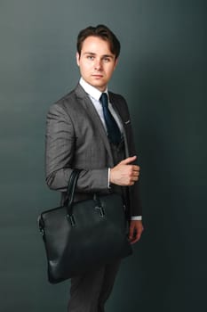 Business and finance concept. Portrait of a businessman who is holding a briefcase. Light background