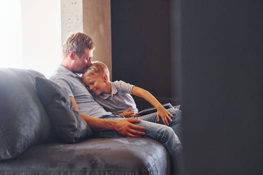 Sitting on the sofa. Father and son is indoors at home together.