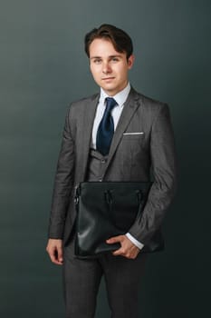 Business and finance concept. Portrait of a businessman who is holding a briefcase. Light background