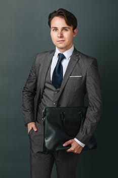 Business and finance concept. Portrait of a businessman who is holding a briefcase. Light background