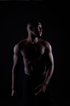 Portrait of athletic african american man topless, black background