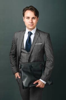 Business and finance concept. Portrait of a businessman who is holding a briefcase. Light background