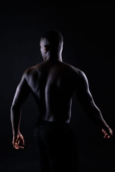 Portrait of athletic african american man topless, black background