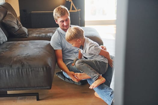 Having free time. Father and son is indoors at home together.