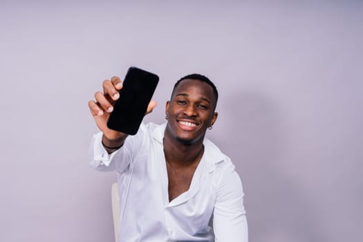 Handsome excited young african business man with a mobile phone isolated over gray background