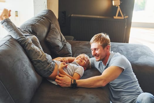 Having fun. Father and son is indoors at home together.