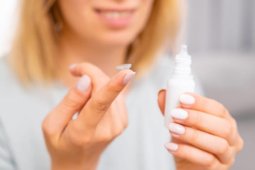 Woman holding contact lens on the finger and eye drop in her hand. Eyecare concept.