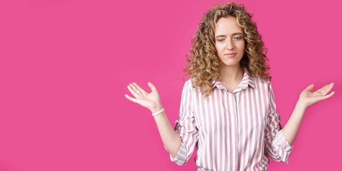 Portrait of a woman who holds her hands up, palms up. Isolated on a pink background.