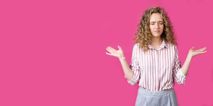 Portrait of a woman who holds her hands up, palms up. Isolated on a pink background.