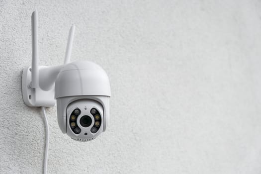 Round CCTV camera with antennas shoots video on the white wall. Digital equipment to record and broadcast real time video closeup