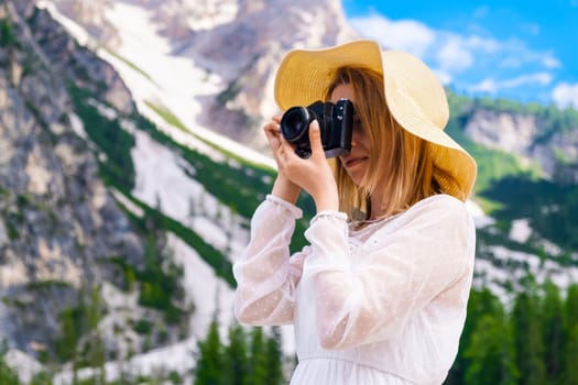 Travel photographer wearing a white dress and hat taking a picture of the amazing Dolomites Alps, Italy