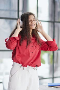 Young freelancer in headphone writing in notebook near laptop in office