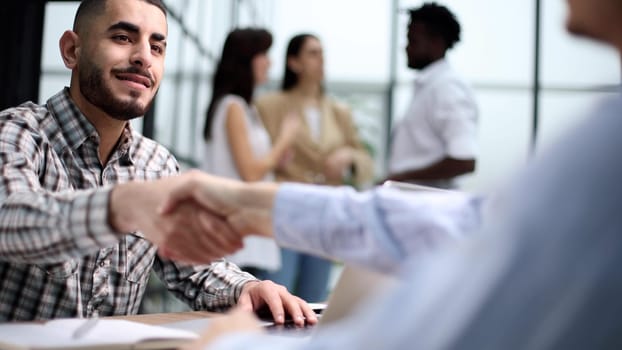 Interview. Young adult caucasian male, hiring manager, sits at a desk in a modern office