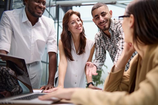 Diverse multinational team having a conversation in a conference room in a creative office.