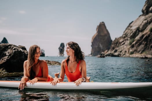 Woman sup yoga. Middle age sporty woman practising yoga pilates on paddle sup surfboard. Female stretching doing workout on sea water. Modern individual hipster outdoor summer sport activity