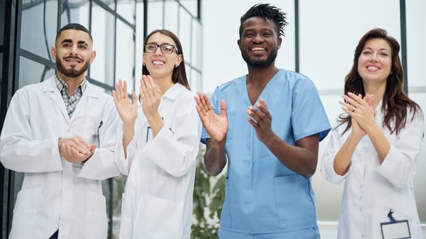 Successful team of different doctors clapping hands in hospital