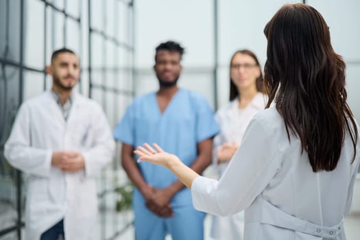 medic woman stands with her back and instructs with colleagues in the hospital