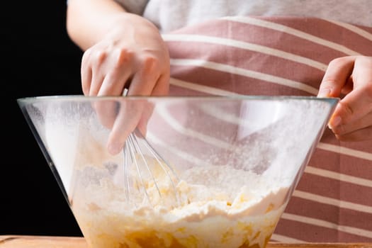 Close up of woman baker hands kneading the dough in the mixing bowl. Homemade pastry for cakes or cookies.