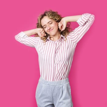 Young woman stretching out her hands after work. Isolated on pink background