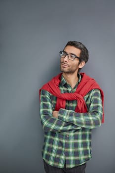 Male beauty. Portrait of a handsome young man with dark hair in glasses on a gray background.