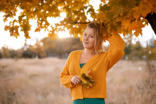 Woman holding autumn leafs in the nature. Autumn woman on leafs background.