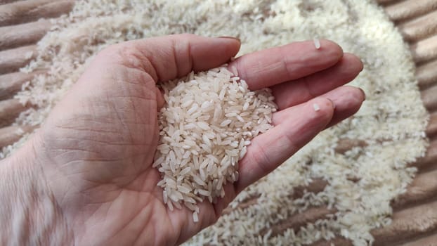 White cereals rice and hand of woman in it. Food for background and texture. Product and food which can be stored for a long time. Partial focus