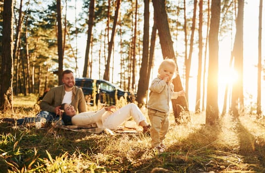 Girl is having a walk. Happy family of father, mother and little daughter is in the forest.