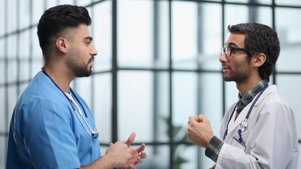 Two doctors men having conversation and one of them has crossed arms