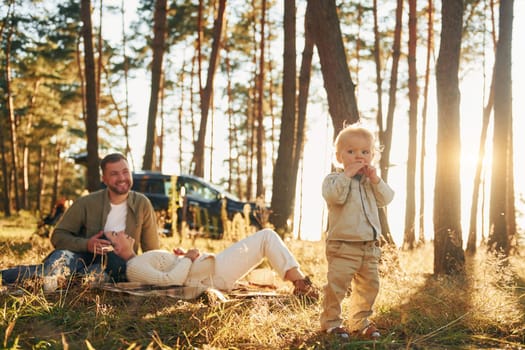 Girl is having a walk. Happy family of father, mother and little daughter is in the forest.