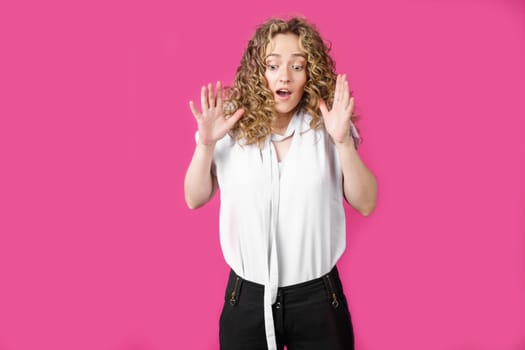 Young woman expressing emotions, raised her hands up. Female portrait. Isolated on pink background