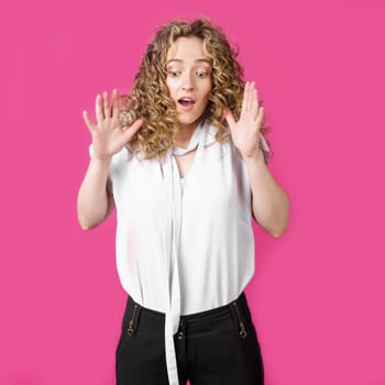 Young woman expressing emotions, raised her hands up. Female portrait. Isolated on pink background