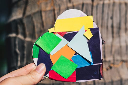 A hand holds a heart made of paper