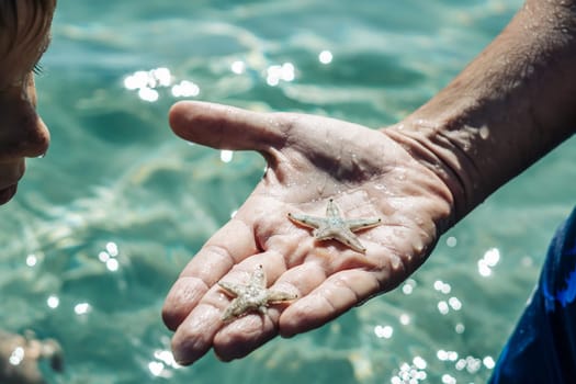 A man holds a starfish in his hand.