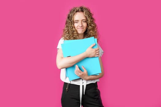 A young woman holds folders with documents in her hands. Isolated on pink background