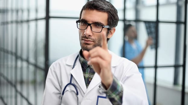attentive doctor in a white coat pointing his finger at you while standing in the corridor of the hospital
