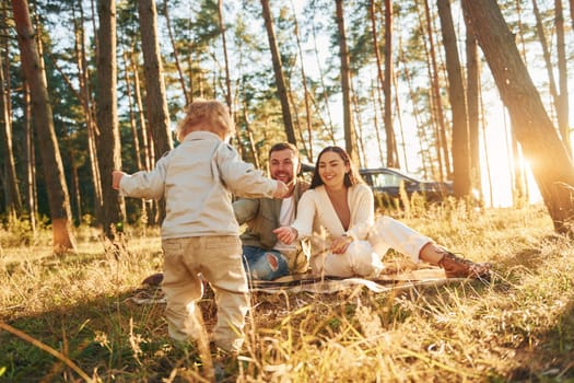 Positive emotions. Happy family of father, mother and little daughter is in the forest.