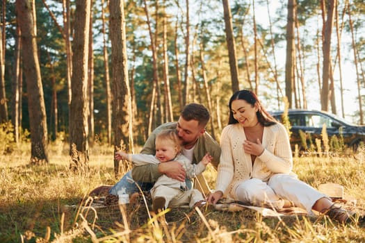 Positive emotions. Happy family of father, mother and little daughter is in the forest.
