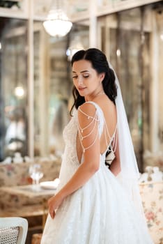 portrait of a bride in a white dress in a bright cafe with mirrors