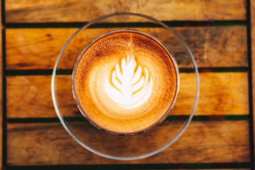 A cup of coffee with a leaf design on the top.