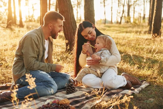 In the forest. Happy family of father, mother and little daughter.