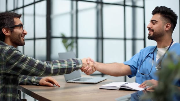 Young doctor shakes hands with a patient in a hospital