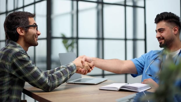 Young doctor shakes hands with a patient in a hospital