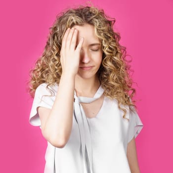 A young woman holds on to her sore head. Female portrait. Isolated on pink background