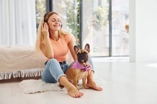 Sitting on the floor. Woman with pug dog is at home at daytime.
