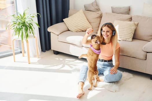 Playing with pet. Woman with pug dog is at home at daytime.