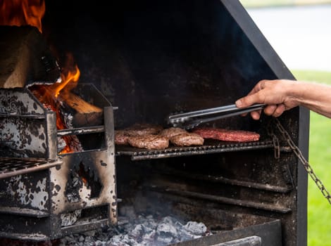 a man is busy turning the burgers on a barbecue over an open fire