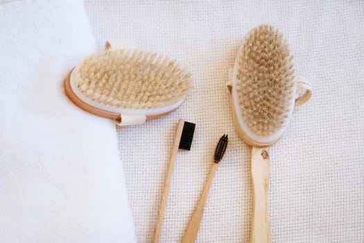 natural wooden massage brushes and dental brushes on a background with a white clothier, the concept of environmentally friendly items for body care