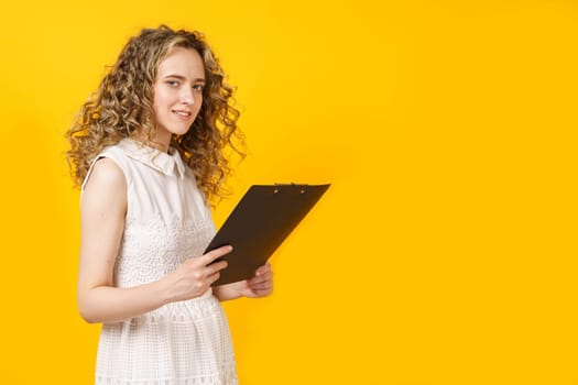 Portrait of a young woman who holds a tablet in her hands. Female portrait. Isolated on yellow background